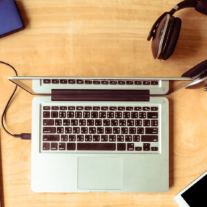 Top view of Electronic devices with notebook, glasses and coffee cup on wooden table background.